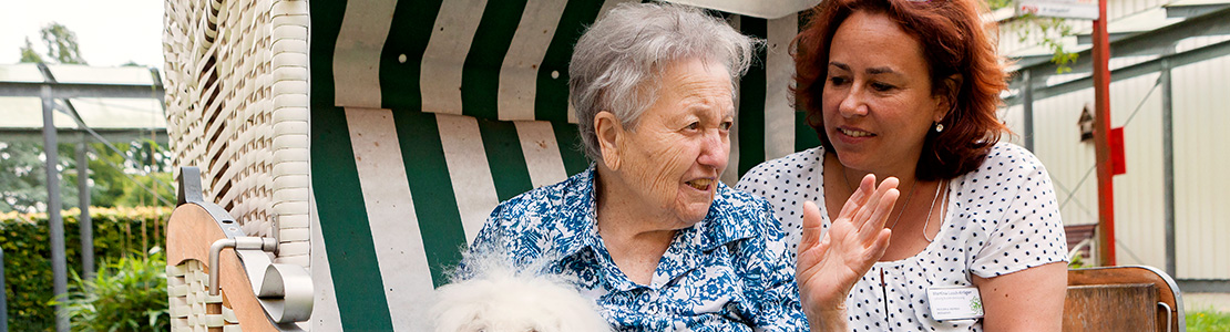 Eine ältere Frau sitzt mit einer anderen Person in einem Strandkorb